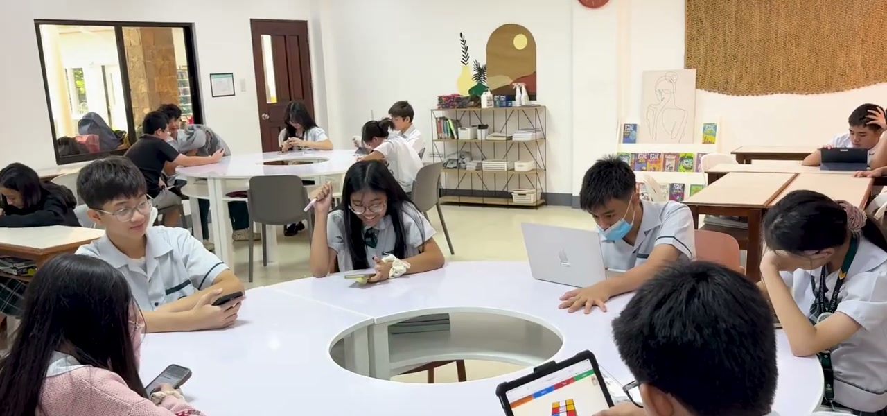 Students working around a round table with iPad and Mac
