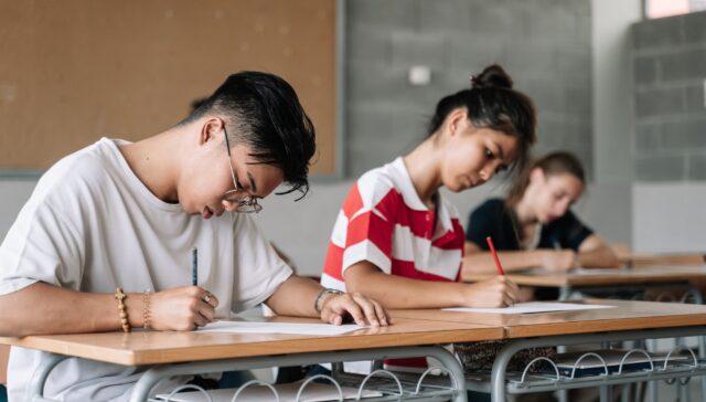 Asian Student writing exam in the college high school classroom