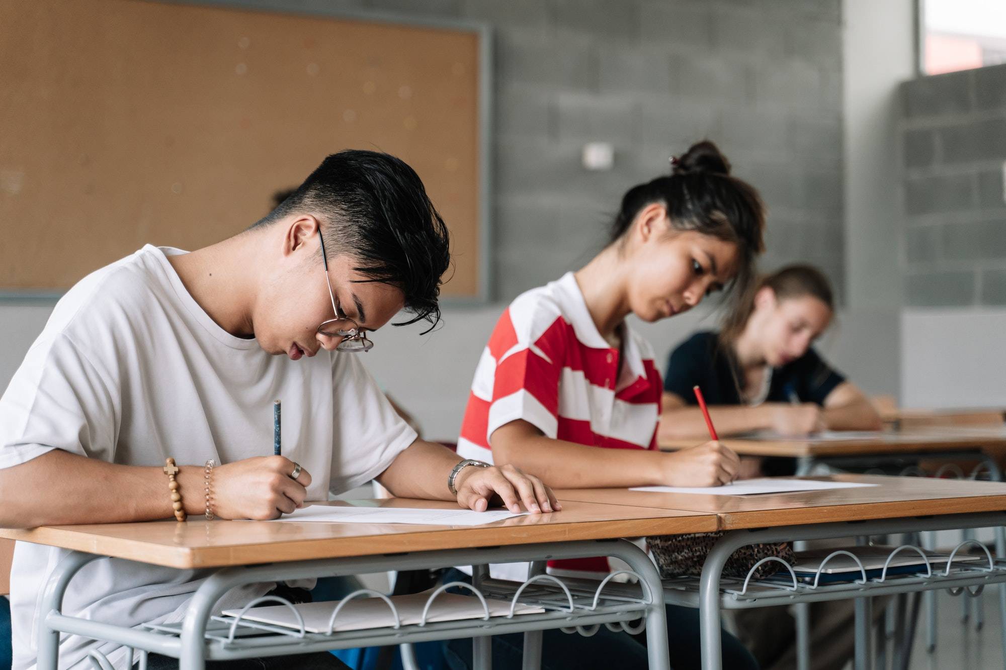 Asian Student writing exam in the college high school classroom